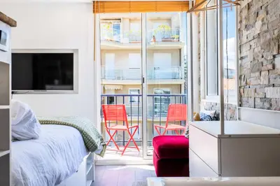 a bedroom with a bed and a balcony with red chairs at Résidence Duplex En Toit-terrasse à Deux Pas De La Croisette - Duplex en toit-terrasse à deux pas de la Croisette MAE-2383 in Cannes