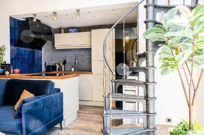 a spiral staircase in a kitchen with a blue couch at Résidence Duplex En Toit-terrasse à Deux Pas De La Croisette - Duplex en toit-terrasse à deux pas de la Croisette MAE-2383 in Cannes