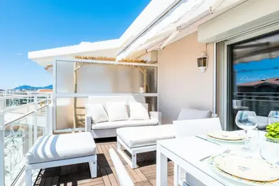 a balcony with white furniture and a table and chairs at Résidence 3p De Standing, Piscine, Vue Mer, à 2 Pas Des Plages - 3P de standing, piscine, vue mer, à 2 pas des plages MAE-2423 in Cannes