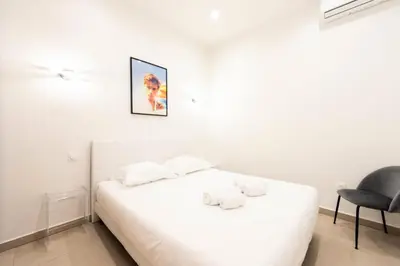 a white bedroom with a bed and a chair at Résidence Appartement Moderne En Plein Centre Ville ! - Appartement moderne en plein centre ville ! MAE-2463 in Cannes