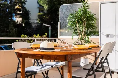 a wooden table with chairs and a hat on a patio at Résidence 3p Lumineux Avec Terrasse à 15min à Pied Du Palais - 3P lumineux avec terrasse à 15min à pied du Palais MAE-2493 in Cannes