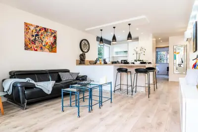 a living room and kitchen with a black couch and stool at Résidence 2 Pièces Terrasse à 8min à Pied Du Centre Parking - 2 pièces terrasse à 8min à pied du centre parking MAE-2553 in Cannes