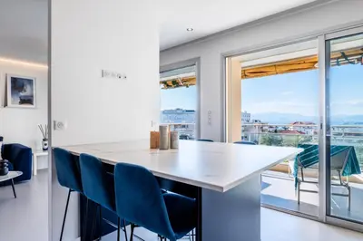 a kitchen with a large white counter and blue chairs at Résidence 4 Pièces Vue Mer, Terrasse Et Parking - 4 pièces vue mer, terrasse et parking MAE-2573 in Cannes
