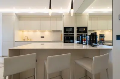 a kitchen with white cabinets and white bar stools at Résidence Rare ! Appartement Grand Standing - Croisette - RARE ! Appartement grand standing - Croisette MAE-2603 in Cannes