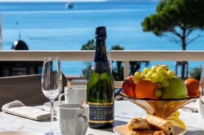 a bottle of wine sitting on a table with a bowl of fruit at Résidence Rare ! Appartement Grand Standing - Croisette - RARE ! Appartement grand standing - Croisette MAE-2603 in Cannes