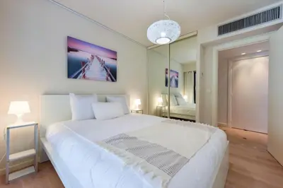 a bedroom with a large white bed and a mirror at Résidence 2p Au Calme, Vue Mer, Piscine Et Garage. - 2P au calme, vue mer, piscine et garage. MAE-2633 in Cannes