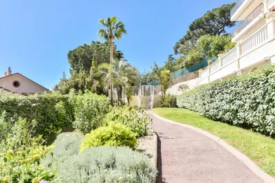 a walkway in a garden next to a building at Résidence 2p Au Calme, Vue Mer, Piscine Et Garage. - 2P au calme, vue mer, piscine et garage. MAE-2633 in Cannes