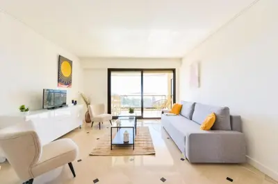 a living room with a couch and a tv at Résidence 2p Au Calme, Vue Mer, Piscine Et Garage. - 2P au calme, vue mer, piscine et garage. MAE-2633 in Cannes