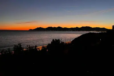 a sunset over the water with mountains in the background at Résidence 3p Vue Mer, Plages à Pied & Parking Privé. - 3P vue mer, plages à pied & parking privé. MAE-2663 in Cannes