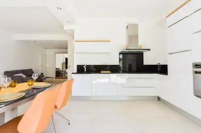 a kitchen with white cabinets and a table and chairs at Résidence Rez-de-jardin, Plages à Pied Et Garage - Rez-de-jardin, plages à pied et garage MAE-2723 in Cannes