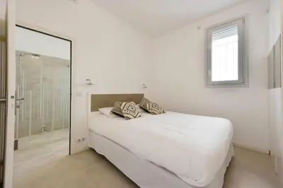 a white bedroom with a bed and a mirror at Résidence Rez-de-jardin, Plages à Pied Et Garage - Rez-de-jardin, plages à pied et garage MAE-2723 in Cannes
