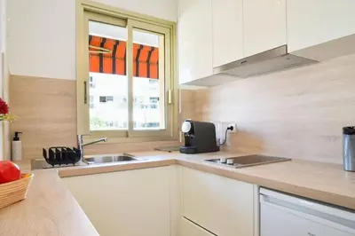 a kitchen with white cabinets and a sink and a window at Résidence Palm Beach Studio Avec Terrasse A 150m Des Plages - Palm Beach studio avec terrasse a 150m des plages MAE-2773 in Cannes