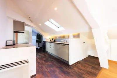 an attic kitchen with white cabinets and wooden floors at Résidence Grand Studio à 3 Min De La Croisette - Grand Studio à 3 min de la Croisette MAE-2823 in Cannes
