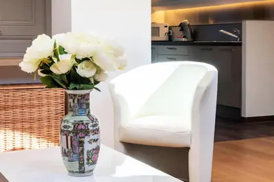a vase with white flowers on a table next to a white chair at Résidence Grand Studio à 3 Min De La Croisette - Grand Studio à 3 min de la Croisette MAE-2823 in Cannes