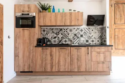 a kitchen with wooden cabinets and a wall at Résidence 3p Centre Cannes Suquet - 3P Centre Cannes Suquet MAE-2903 in Cannes