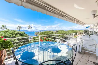 a balcony with a table and chairs and a swimming pool at Résidence Vue Mer 95m2 Grande Terrasse Cannes Croisette. - Vue mer 95m2 Grande Terrasse Cannes Croisette. MAE-3003 in Cannes