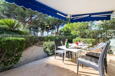 a table and chairs under an umbrella on a patio at Résidence Rez-de-jardin Croisette Vue Mer Avec Garage - Rez-de-jardin Croisette vue mer avec garage MAE-3083 in Cannes