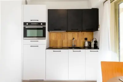 a kitchen with white cabinets and a black oven at Résidence Studio Terrasse 2 Min De La Croisette - Studio Terrasse 2 min de la Croisette MAE-3113 in Cannes