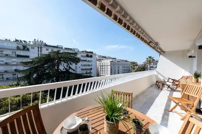 a balcony with wooden tables and chairs on a building at Résidence Grand 2p Rénové Terrasse Cœur De Cannes - Grand 2P rénové Terrasse Cœur de Cannes MAE-3143 in Cannes