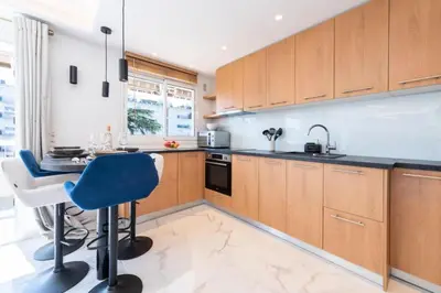 a kitchen with wooden cabinets and a blue chair at Résidence Grand 2p Rénové Terrasse Cœur De Cannes - Grand 2P rénové Terrasse Cœur de Cannes MAE-3143 in Cannes