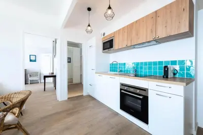 a kitchen with white cabinets and blue tile on the wall at Résidence Cannes – Suquet Vue Mer & Accès Plage - Cannes – Suquet Vue Mer & Accès Plage MAE-3163 in Cannes