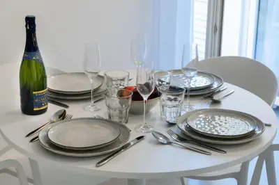 a white table with plates and glasses and a bottle of wine at Résidence 3p Terrasse & Calme Cannes Centre - 3P Terrasse & Calme Cannes Centre MAE-3213 in Cannes