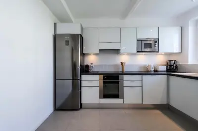 a kitchen with white cabinets and a stainless steel refrigerator at Résidence 3p Terrasse & Calme Cannes Centre - 3P Terrasse & Calme Cannes Centre MAE-3213 in Cannes