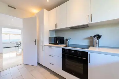 a kitchen with white cabinets and a black appliance at Résidence 3p Vue Mer, Piscine – Cannes Croix Des Gardes - 3P Vue Mer, Piscine – Cannes Croix des Gardes MAE-3273 in Cannes