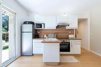a kitchen with white cabinets and a refrigerator at Résidence 2p Rez-de-jardin Au Calme – Cadre Paisible - 2P Rez-de-jardin au calme – Cadre Paisible MAE-3313 in Cannes