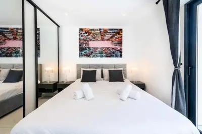 a white bedroom with a large white bed with mirrors at Résidence 2p Traversant, Centre Cannes, Rue D’antibes - 2P Traversant, Centre Cannes, Rue d’Antibes MAE-3343 in Cannes