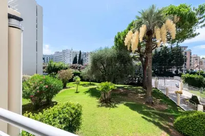 a balcony with a yard with a palm tree and bushes at Résidence 3p Résidence Avec Piscine, Proche Croisette - 3P Résidence avec piscine, proche Croisette MAE-2773 in Cannes