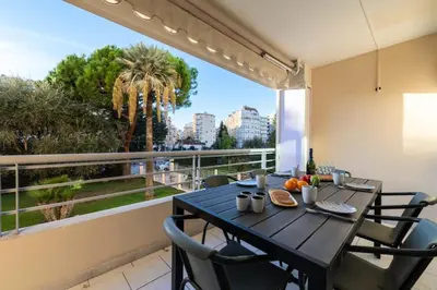 a dining table on a balcony with a view of a palm tree at Résidence 3p Résidence Avec Piscine, Proche Croisette - 3P Résidence avec piscine, proche Croisette MAE-2773 in Cannes