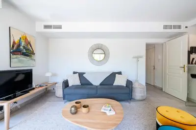 a living room with a blue couch and a table at Résidence 2p Rez-de-jardin Avec Piscine – Calme, Parking Privé - 2P Rez-de-jardin avec piscine – Calme, Parking privé MAE-2133 in Cannes