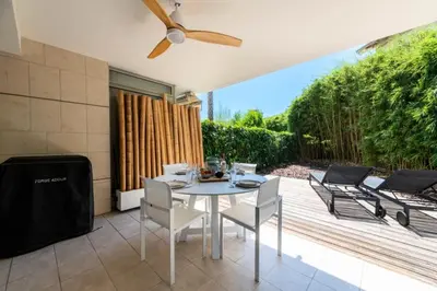 a patio with a table and chairs and a fan at Résidence 2p Rez-de-jardin Avec Piscine – Calme, Parking Privé - 2P Rez-de-jardin avec piscine – Calme, Parking privé MAE-2133 in Cannes