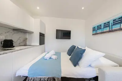 a white kitchen with a bed with blue and white pillows at Résidence Cannes 2p Proche Centre - Cannes 2P Proche Centre MAE-4093 in Cannes