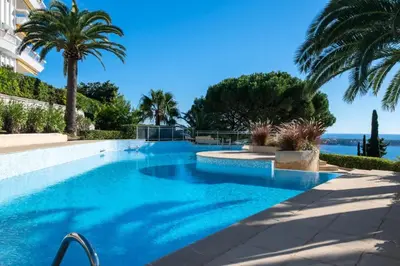 a swimming pool with blue water and palm trees at Résidence 3p Vue Panoramique - Dernier Étage, Cannes - 3P Vue Panoramique - Dernier Étage, Cannes MAE-3933 in Cannes