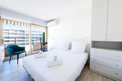 a white bedroom with a large white bed and a blue chair at Résidence 3p Vue Panoramique & Accès Plages - 3P Vue Panoramique & Accès Plages MAE-5013 in Cannes
