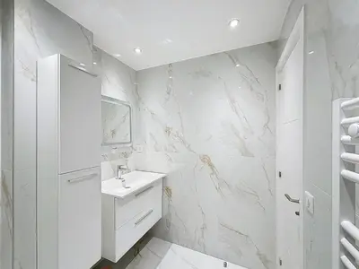 a white bathroom with a sink and a marble wall at Executive 2BR Apartment near Croisette Ideal for MIPIM Terrace & Wi-Fi in Cannes