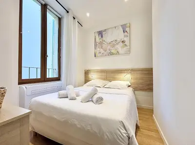 a bedroom with a bed with white sheets and a window at Cannes One Bedroom Apartment - 85M in Cannes