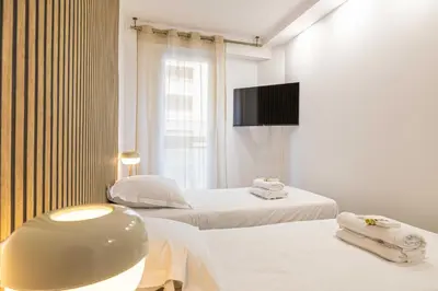 a white room with two beds and a tv at Elegant apt with balcony near the beaches – Cannes in Cannes