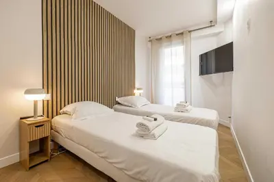 two beds in a small room with a tv at Elegant apt with balcony near the beaches – Cannes in Cannes