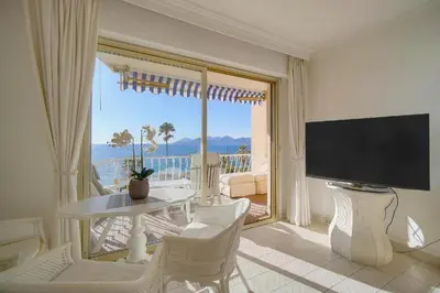 a living room with a television and a table and chairs at Cannes Sunset & Sea Apartment in Cannes