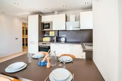 a kitchen with white cabinets and a dining table with chairs at Résidence 3p De Style, Résidence Sécurisée Sur La Croisette - 3P de style, résidence sécurisée sur la Croisette MAE-1993 in Cannes