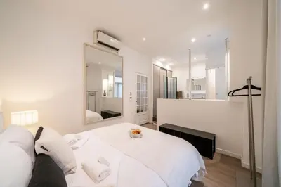 a white bedroom with a bed and a mirror at Hyper centre Cannes - 2 pièces avec balcon - 4 couchages in Cannes