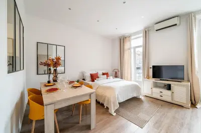 a white bedroom with a bed and a table and chairs at Hyper centre Cannes - 2 pièces avec balcon - 4 couchages in Cannes