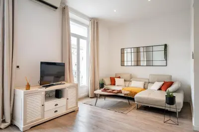 a living room with a couch and a tv at Hyper centre Cannes - 2 pièces avec balcon - 4 couchages in Cannes