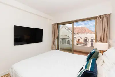 a white bedroom with a bed and a large window at 5 Croisette 6 in Cannes