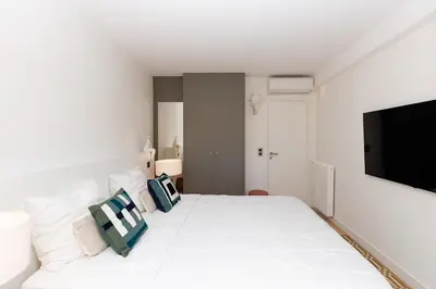 a white bedroom with a large white bed with pillows at 5 Croisette 6 in Cannes