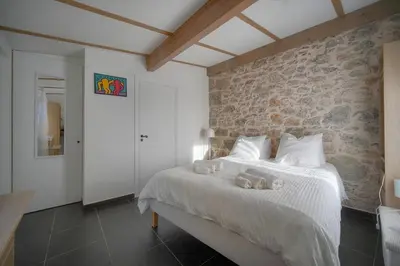 a bedroom with a white bed with a stone wall at MAISON DE VILLE 6 Chambres TERRASSE -Stanislas Chic A6B002 in Cannes