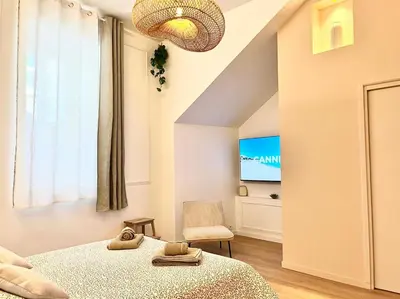 a bedroom with a bed and a chair and a tv at Le Borniol in Cannes